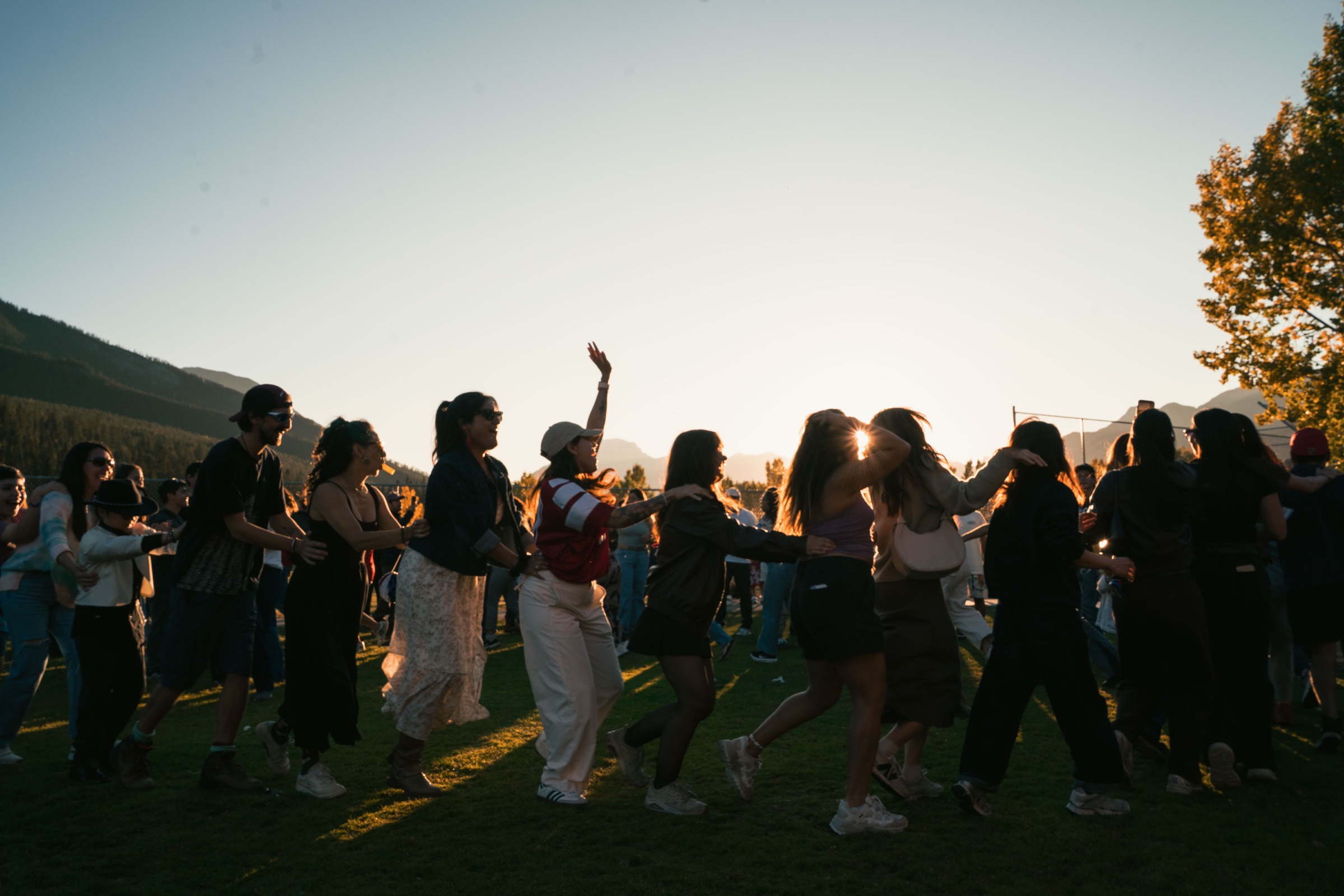 People dancing together outdoors at sunset in the Bow Valley