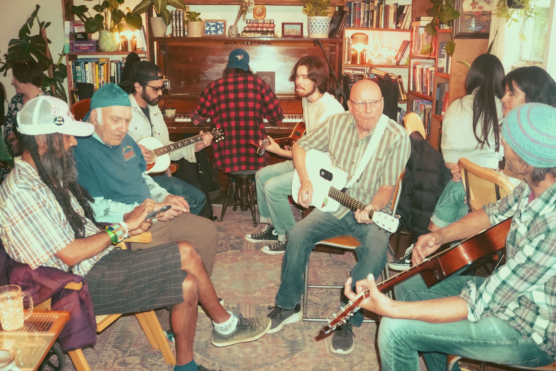 A group gathered around a piano and guitars